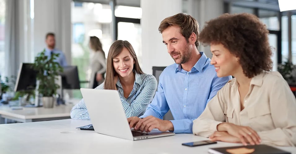 Business professionals collaborating in an office around a laptop