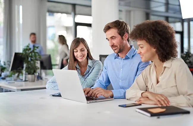 Business professionals collaborating in an office around a laptop