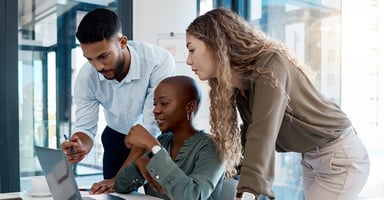 Colleagues collaborating around a laptop