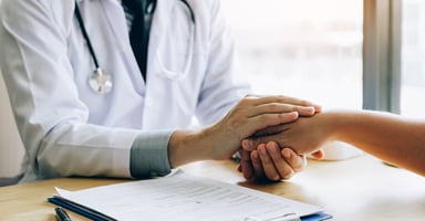 Doctor holding a patient's hand over a desk