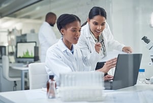 Two women technicians using a laptop in a laboratory.