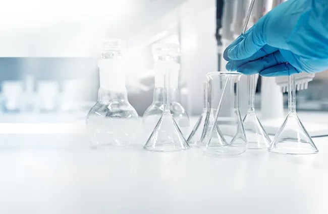 Gloved worker working with beakers in a laboratory