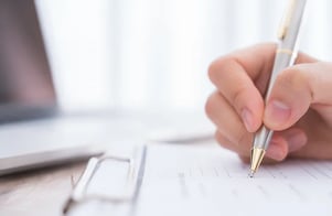 Hand writing on clipboard with a pen