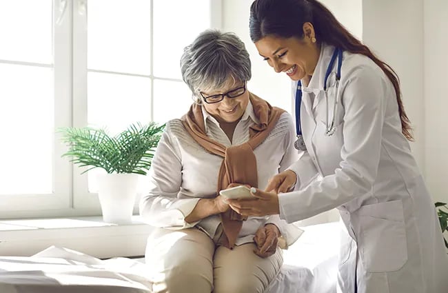 Health care worker showing patient something on mobile phone