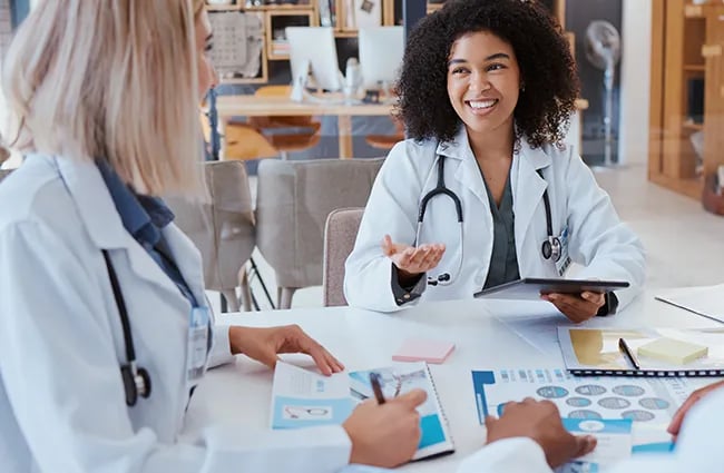 Healthcare professionals in lab coats conversing around a table