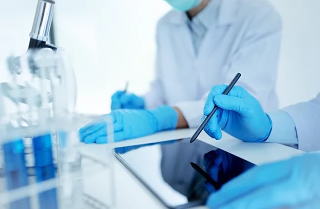 Lab techs working at a desk with tablet devices
