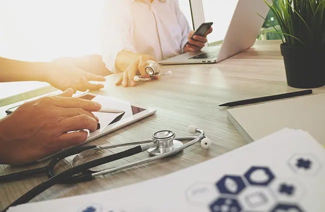 People working at a table with medical and computer devices