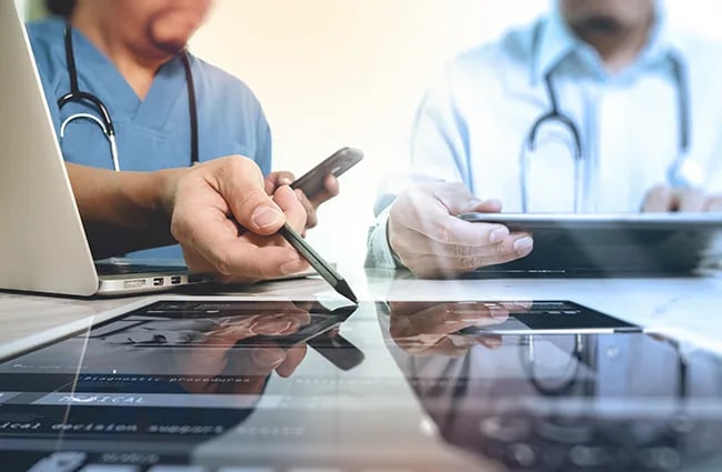 Person holding pen pointing to tablet device on a table