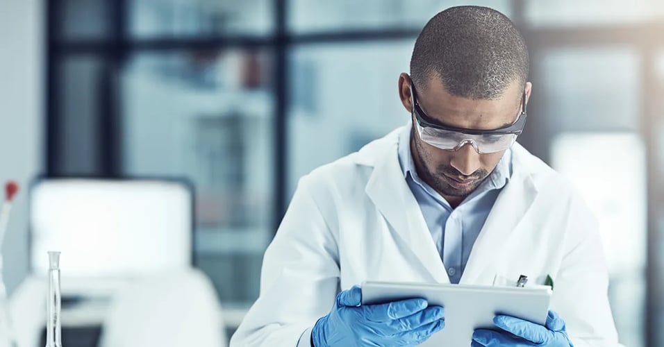 Person wearing protective equipment reviewing a tablet device