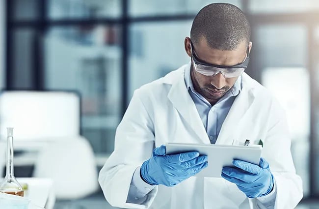 Person wearing protective equipment reviewing a tablet device