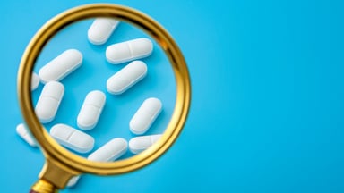 White pills behind magnifying glass