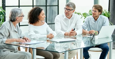 Several business professionals talking around glass conference table