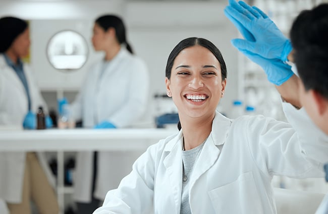 smiling-woman-high-fiving-coworker-as-983431523-650x425