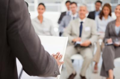 Shoulder of a man at a podium addressing an audience