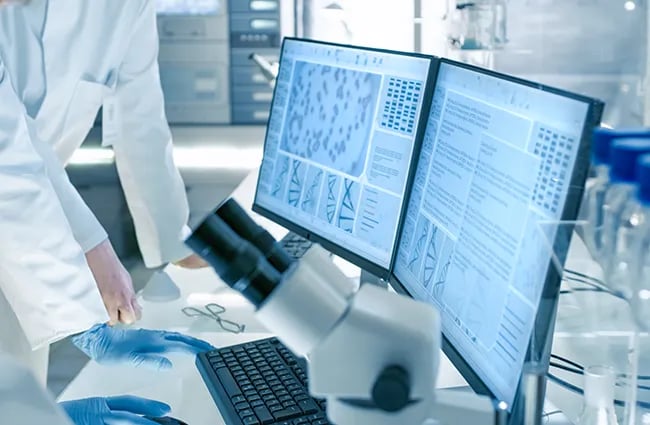 Two computer monitors showing cell and DNA data