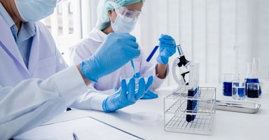 Two lab techs working with petri dishes test tubs in clean room