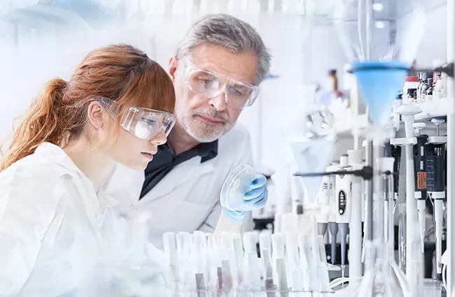 Two lab workers looking at material in a petridish