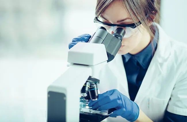 Woman technician looking into microscope