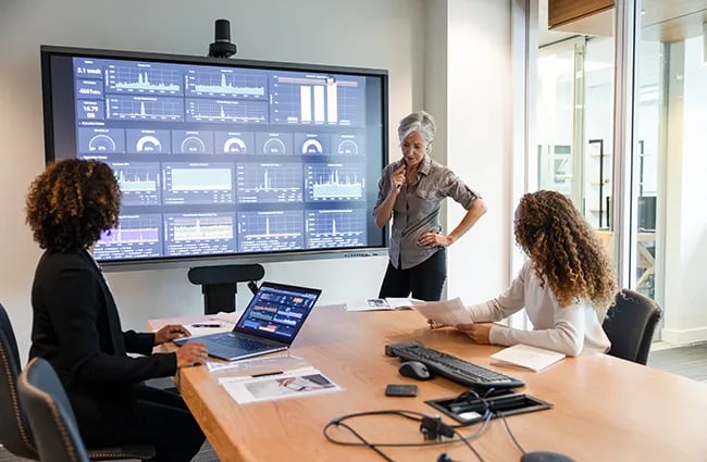Women working in conference room discussing various data and charts